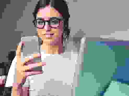 Girl with glasses smiling looking at her phone